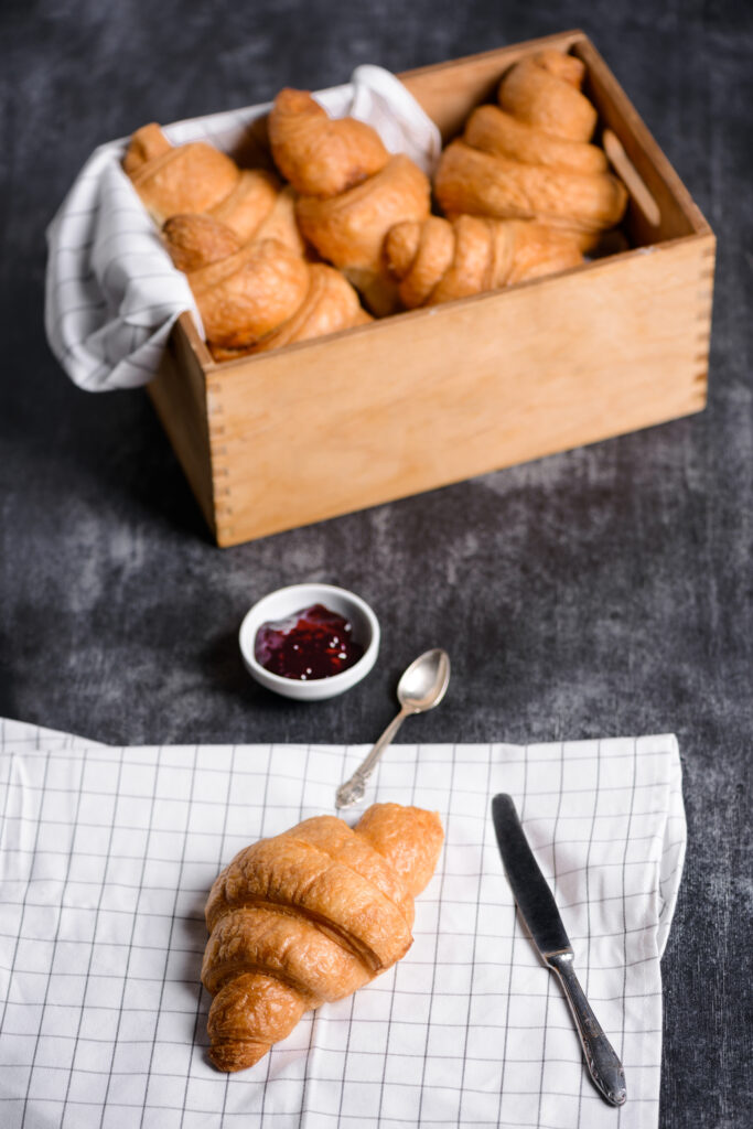 croissants wooden box jam pot aside grey table
